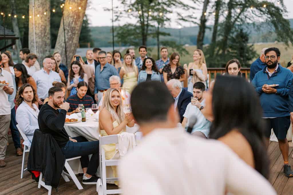 Guests gathered on the outdoor deck during Sara and Kevin's rehearsal dinner and wedding weekend at Skytop Lodge, with string lights and mountain views in the Pocono Mountains