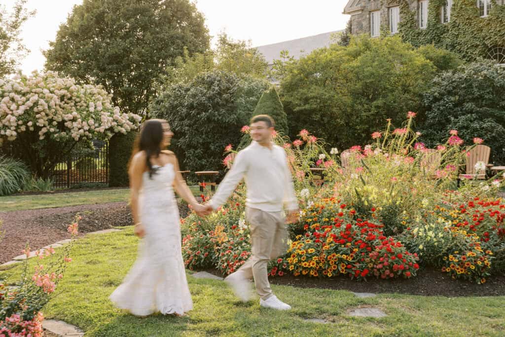 Artistic motion blur image of bride and groom holding hands and walking through the colorful gardens at Skytop Lodge during their rehearsal dinner evening portraits