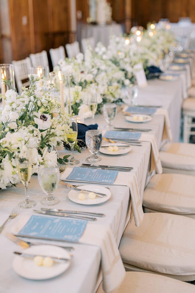 White anemone and garden floral centerpieces with dusty blue menus and candlelight at a Skytop Lodge wedding reception in Skytop, Pennsylvania