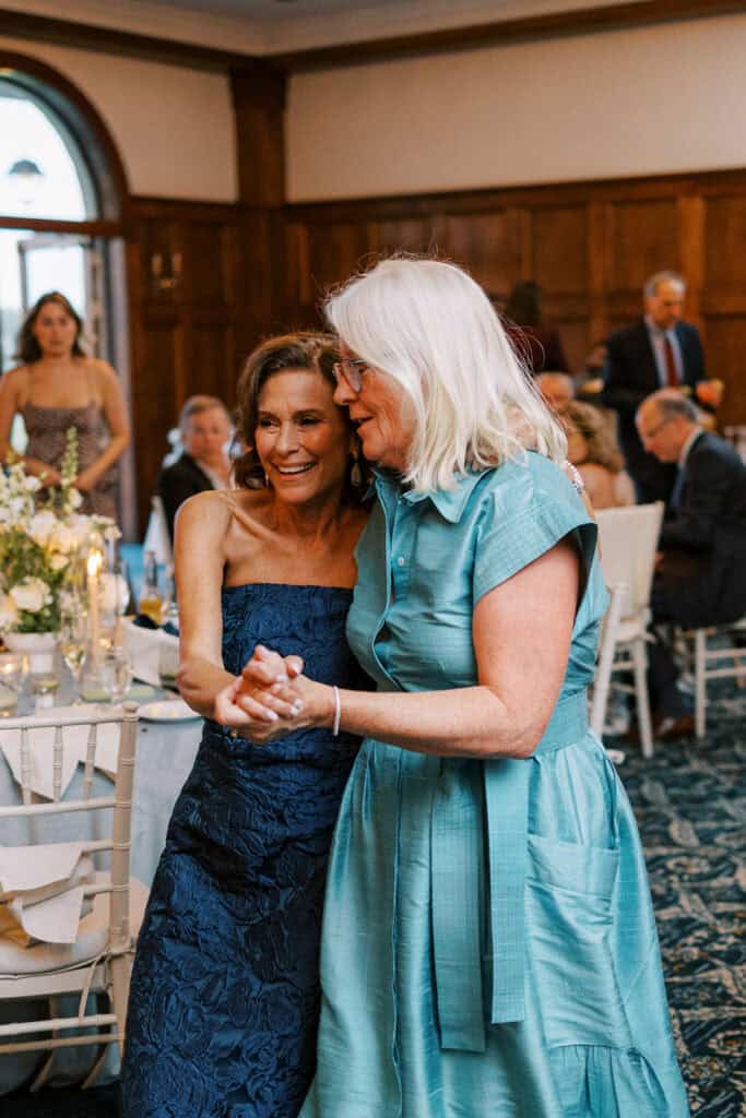 Two wedding guests embracing and dancing together in the wood-paneled ballroom at a Skytop Lodge wedding reception in Skytop, Pennsylvania