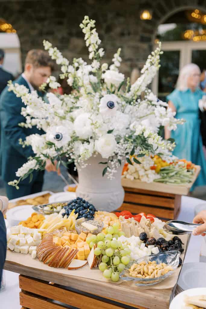 Outdoor cocktail hour charcuterie display with white anemone and delphinium floral arrangement at a Skytop Lodge wedding reception in Skytop, Pennsylvania