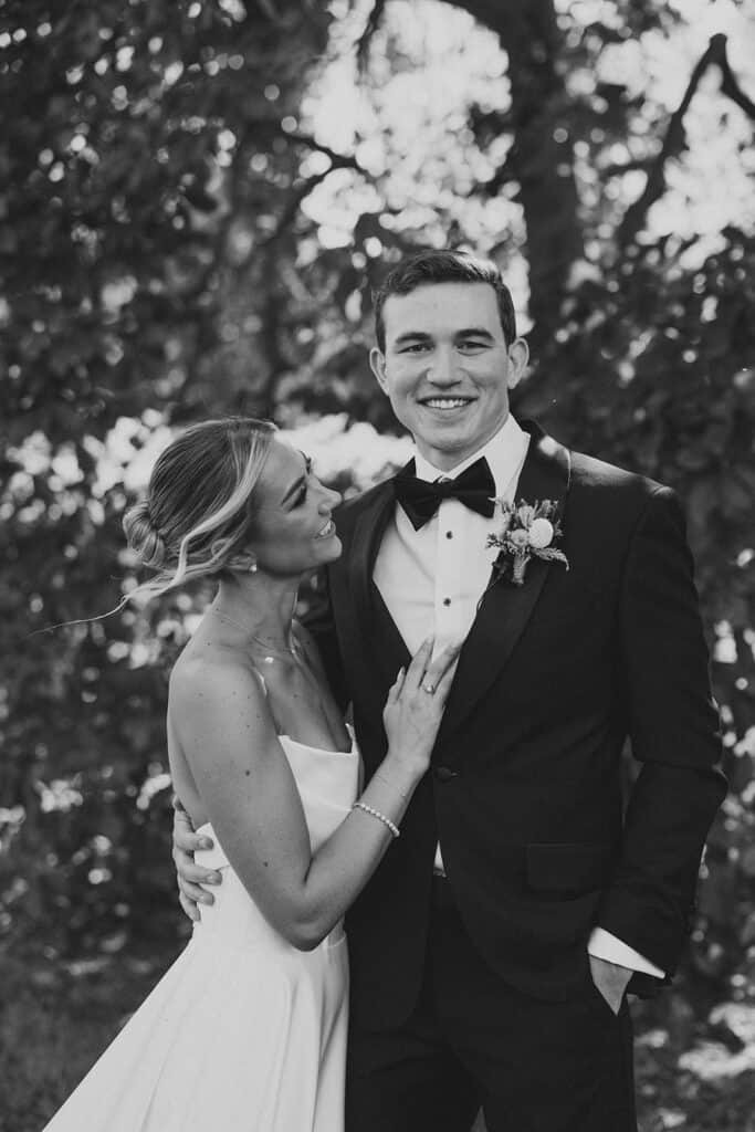 Black and white couple portrait of bride leaning into groom's chest while he smiles at camera, Tyler Arboretum fall wedding Media PA, photographed by Philadelphia wedding photographer Samantha Jay Photo