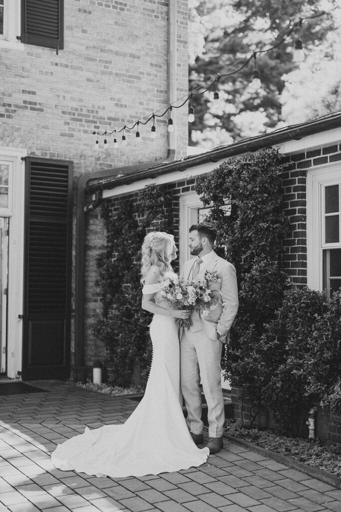 Black and white portrait of bride and groom in front of ivy-covered brick mansion at Drumore Estate wedding in Lancaster PA