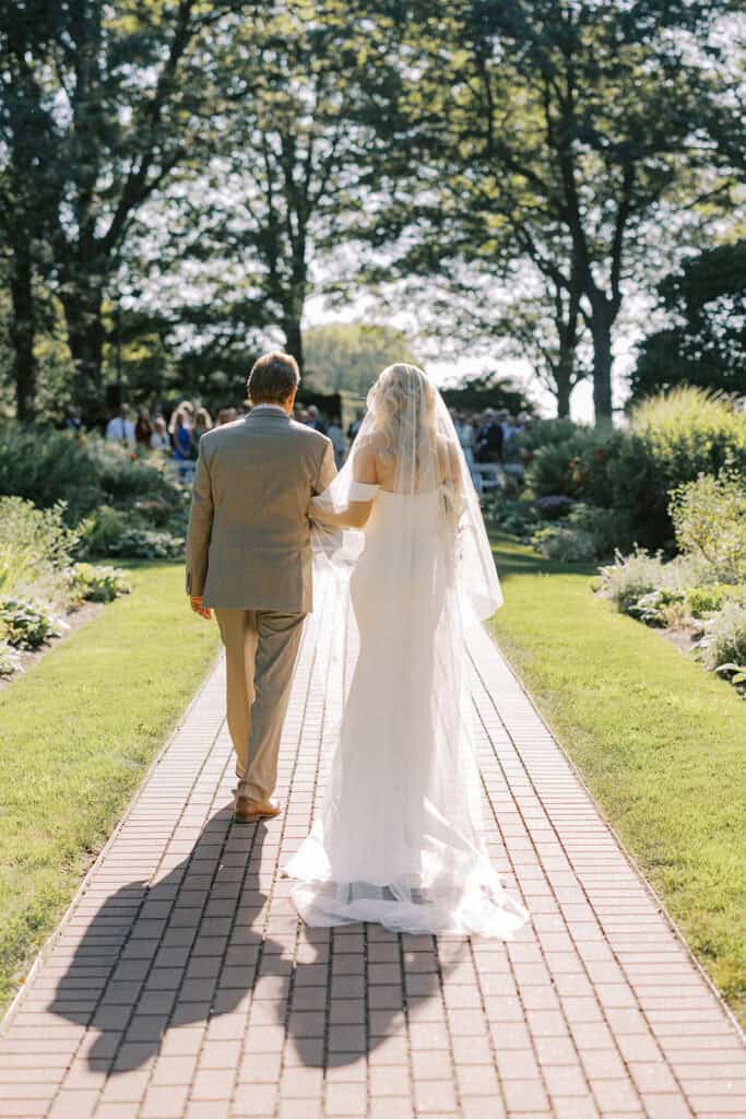 Father walking bride down brick aisle at Drumore Estate outdoor summer wedding ceremony in Lancaster County Pennsylvania