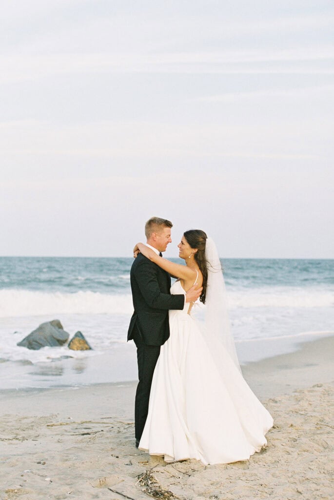 Bride and groom embracing at the shoreline during their Rehoboth Beach wedding, Delaware film photographer