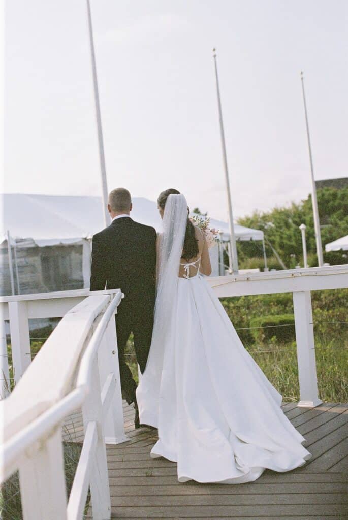 Bride and groom walking toward their reception tent at Rehoboth Beach, Delaware wedding photographed on film