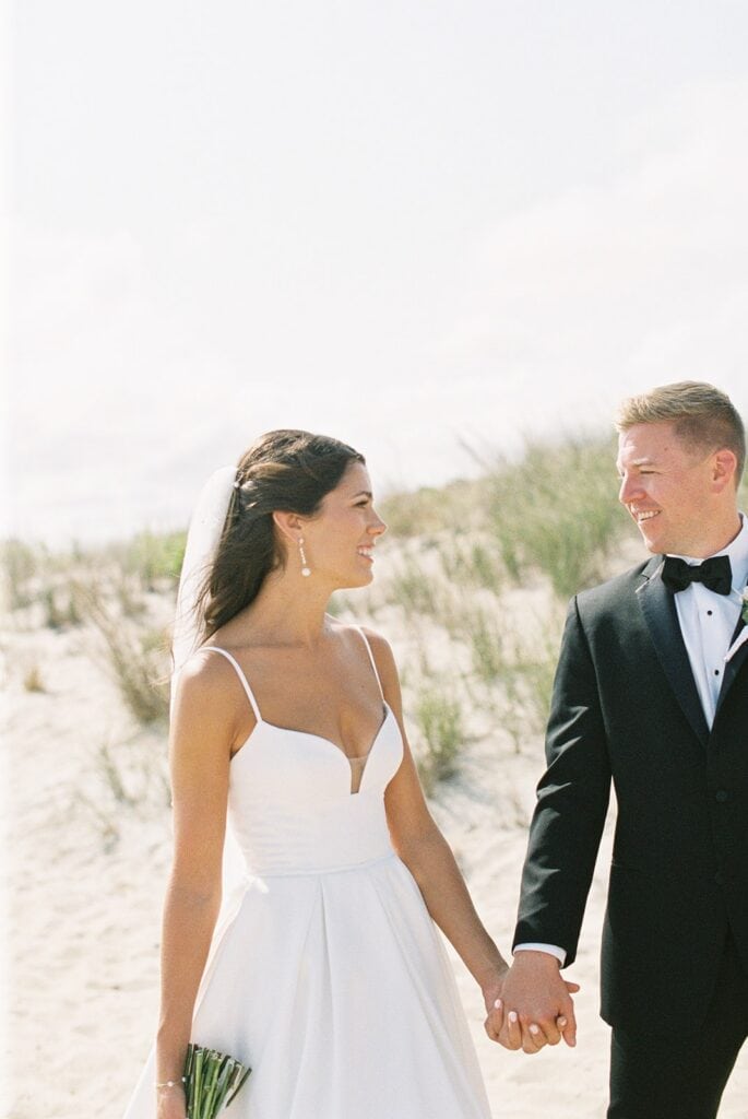 Bride and groom laughing together on Rehoboth Beach sand dunes, Delaware film wedding photographer Samantha Jay Photo