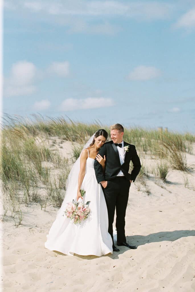 Bride leaning into groom with pink bridal bouquet on Rehoboth Beach, Delaware film wedding photography
