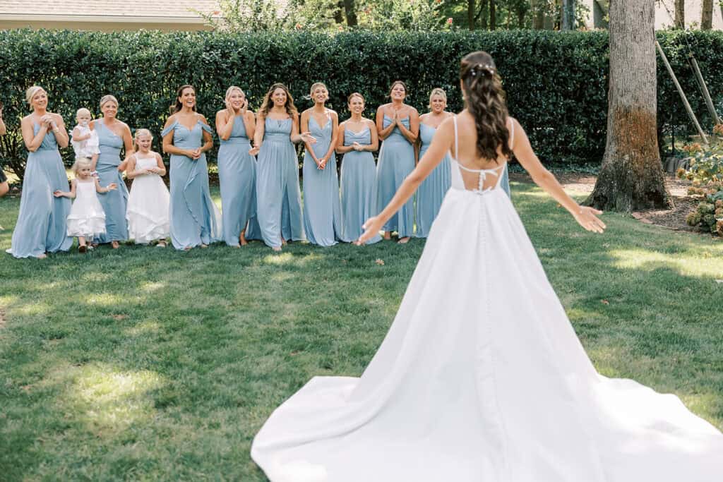 Bride revealing her wedding dress to bridesmaids in dusty blue gowns during getting ready at Rehoboth Beach wedding, Samantha Jay Photo