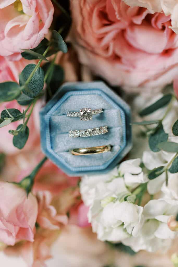 Diamond engagement ring and wedding bands in blue velvet ring box surrounded by pink garden roses, Rehoboth Beach wedding photography
