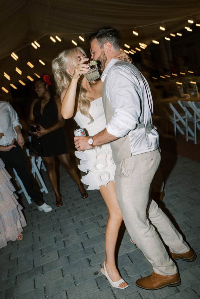 Bride and groom dancing and drinking cocktails at Drumore Estate summer wedding reception under tent lighting