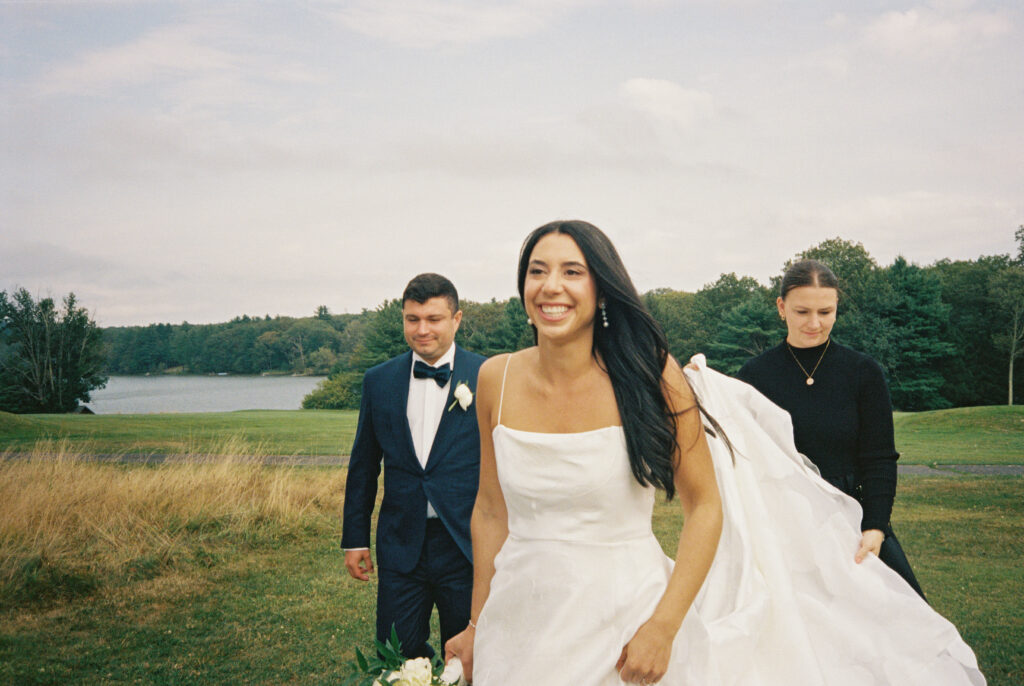 Day of wedding planner helps the bride carry her train in between wedding day portraits at Skytop Lodge in Skytop, Pennsylvania for an easy and seamless photography process