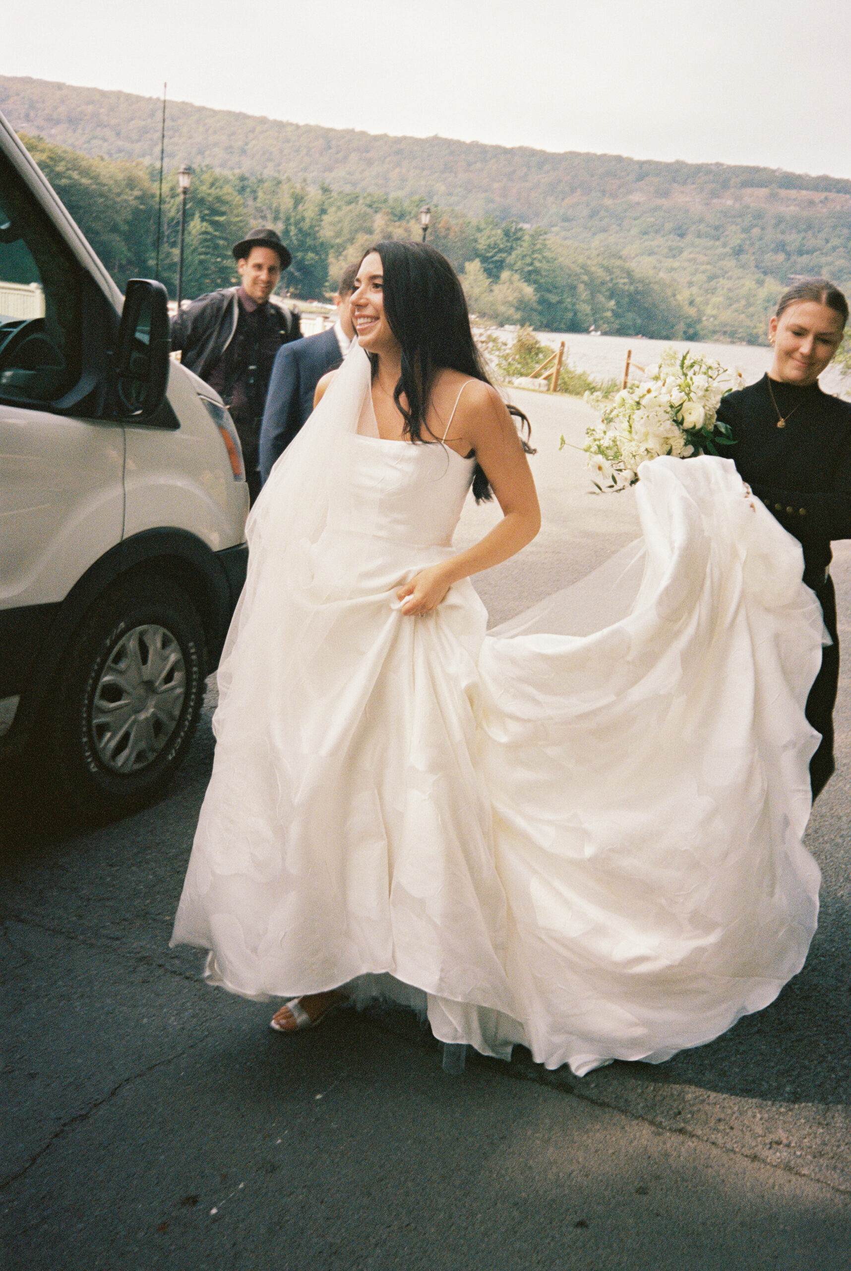Wedding planner from Courtney Space Events carries the bride's train during wedding day portraits at Skytop Lodge in Skytop, Pennsylvania