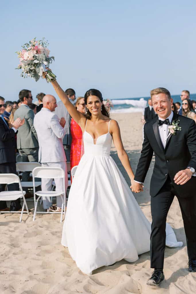 Bride raising bouquet in celebration after beach wedding ceremony recessional at Rehoboth Beach Delaware, Samantha Jay Photo