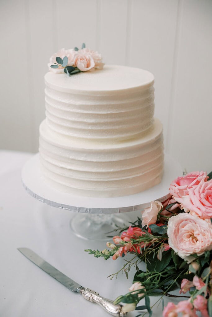 wo-tier white wedding cake with blush roses and eucalyptus at Rehoboth Beach Delaware wedding, Samantha Jay Photo