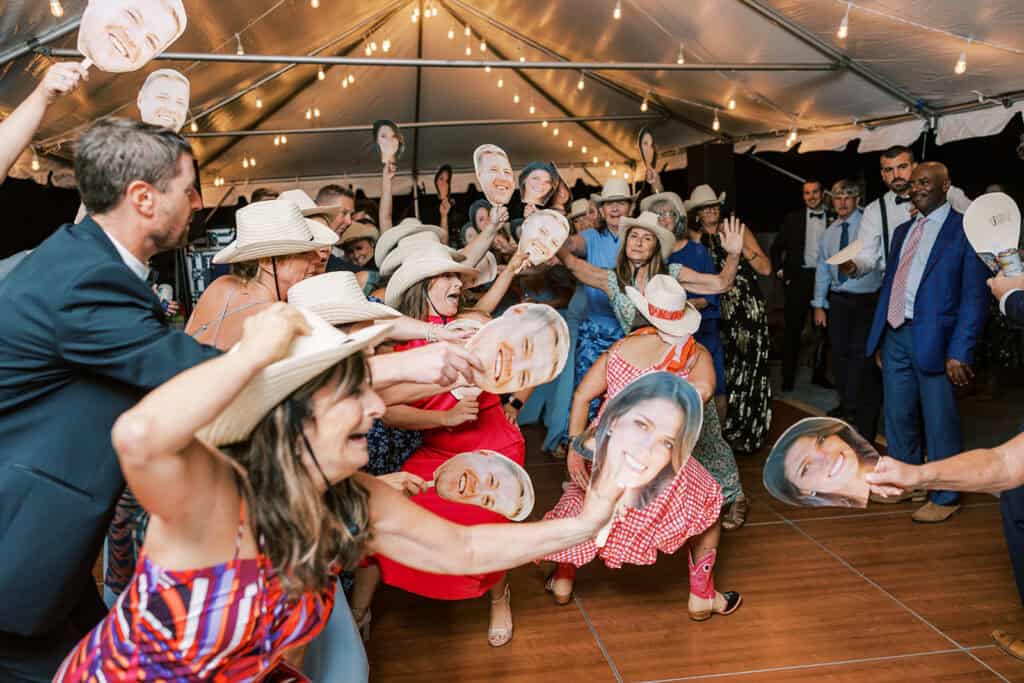 Wedding guests dancing with oversized bride and groom face fans at Rehoboth Beach Delaware wedding reception, Henlopen Acres Beach Club
