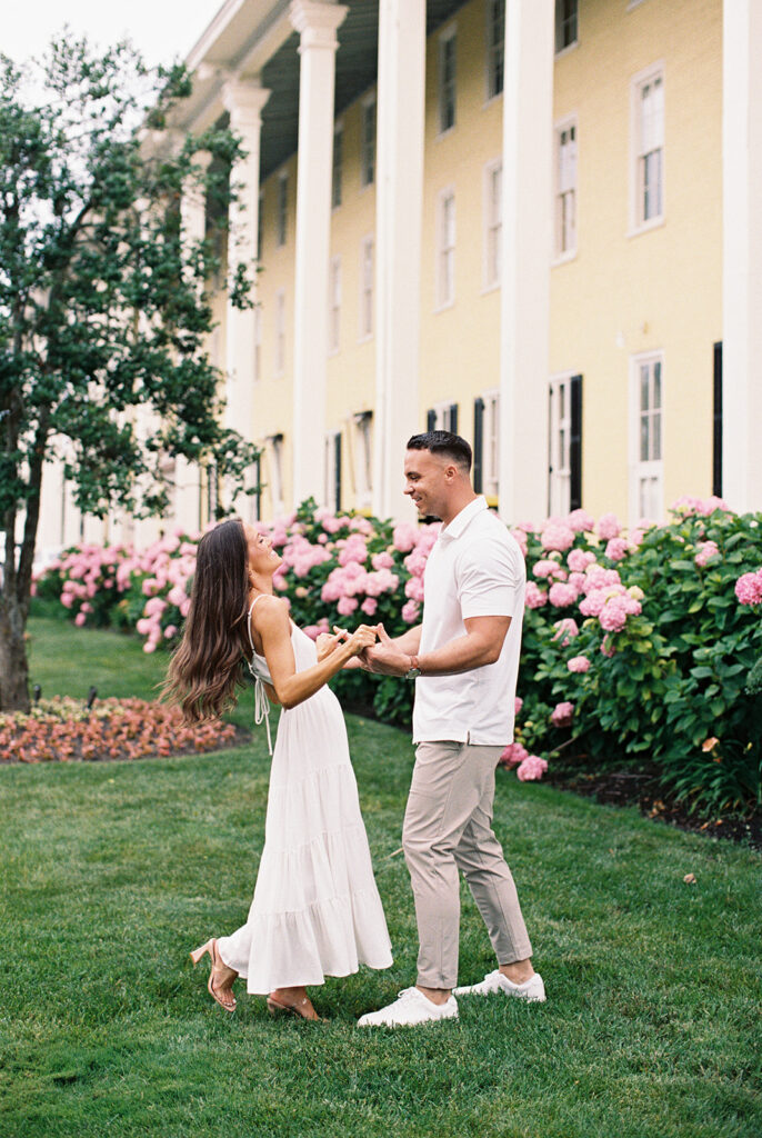 Carolyn and Zach dancing on the lawn in front of Congress Hall's pink hydrangeas during their summer Cape May engagement session