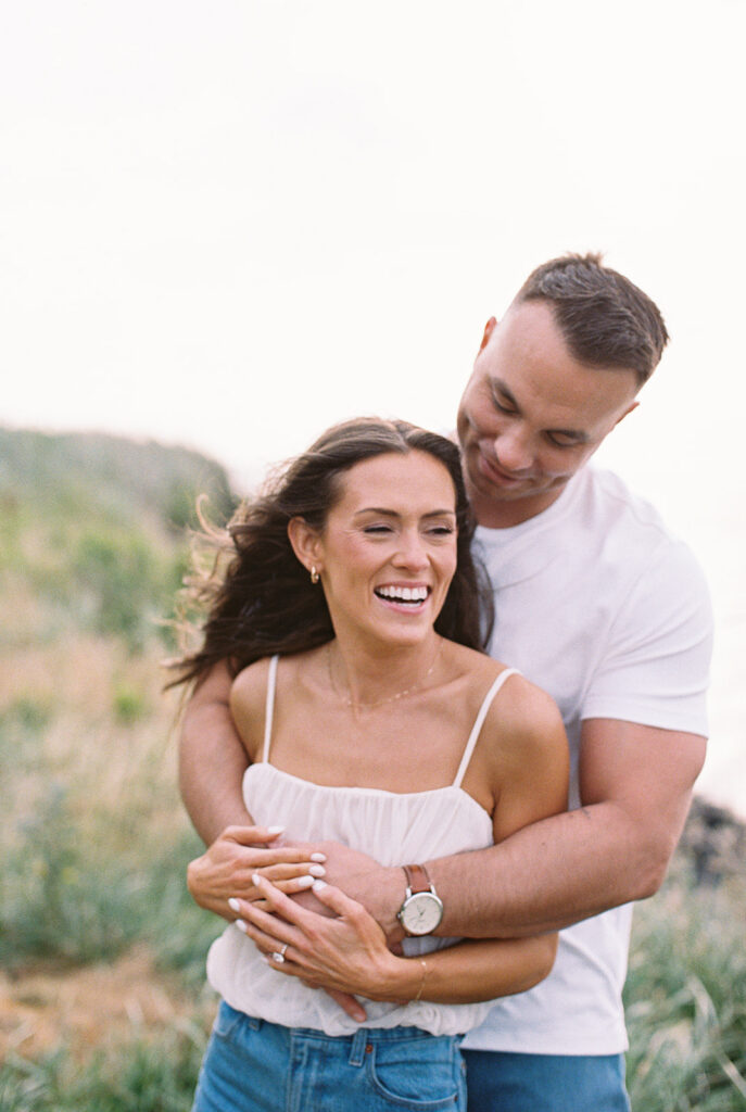 Candid portrait of an engaged couple laughing together in the dune grass at their Cape May engagement session