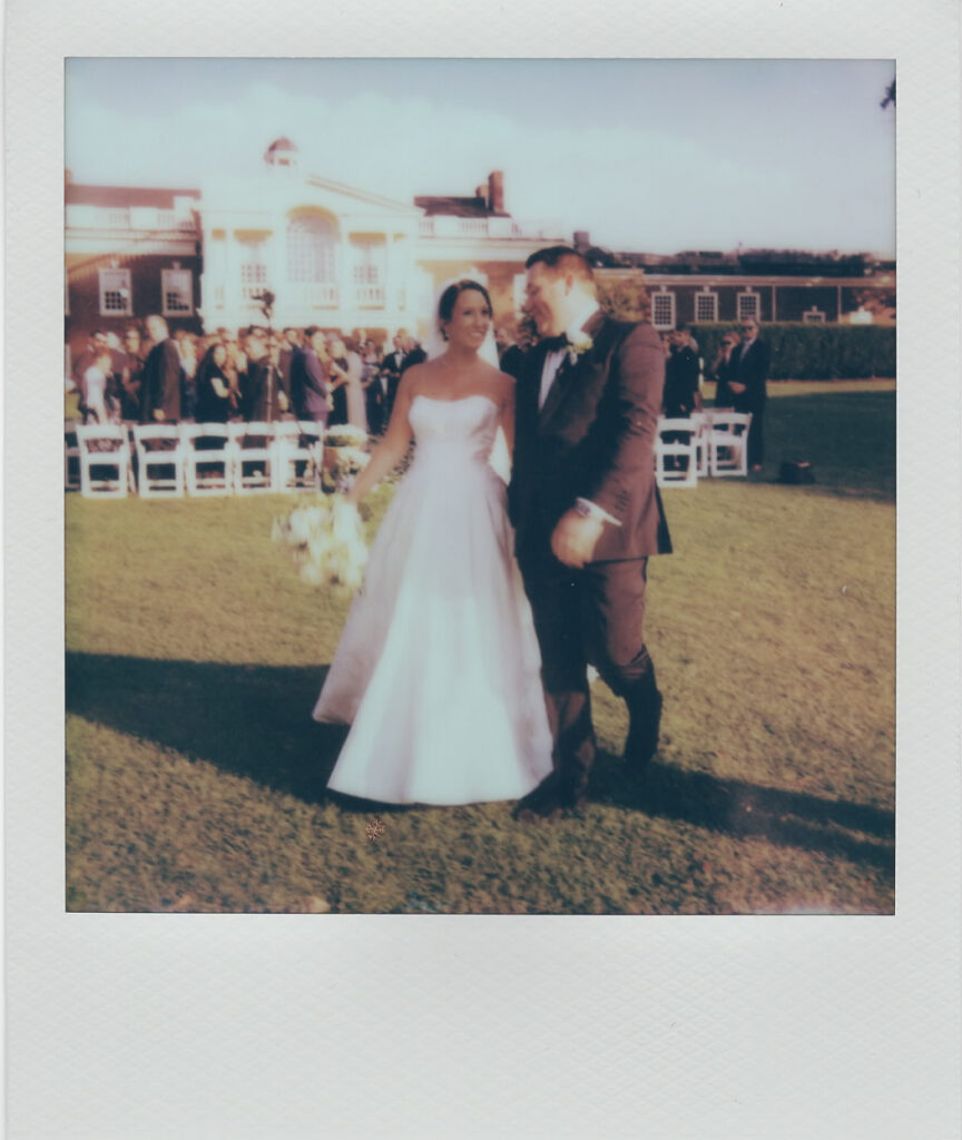Polaroid of the newlyweds walking together on the lawn in front of the Philadelphia Cricket Club clubhouse after their ceremony