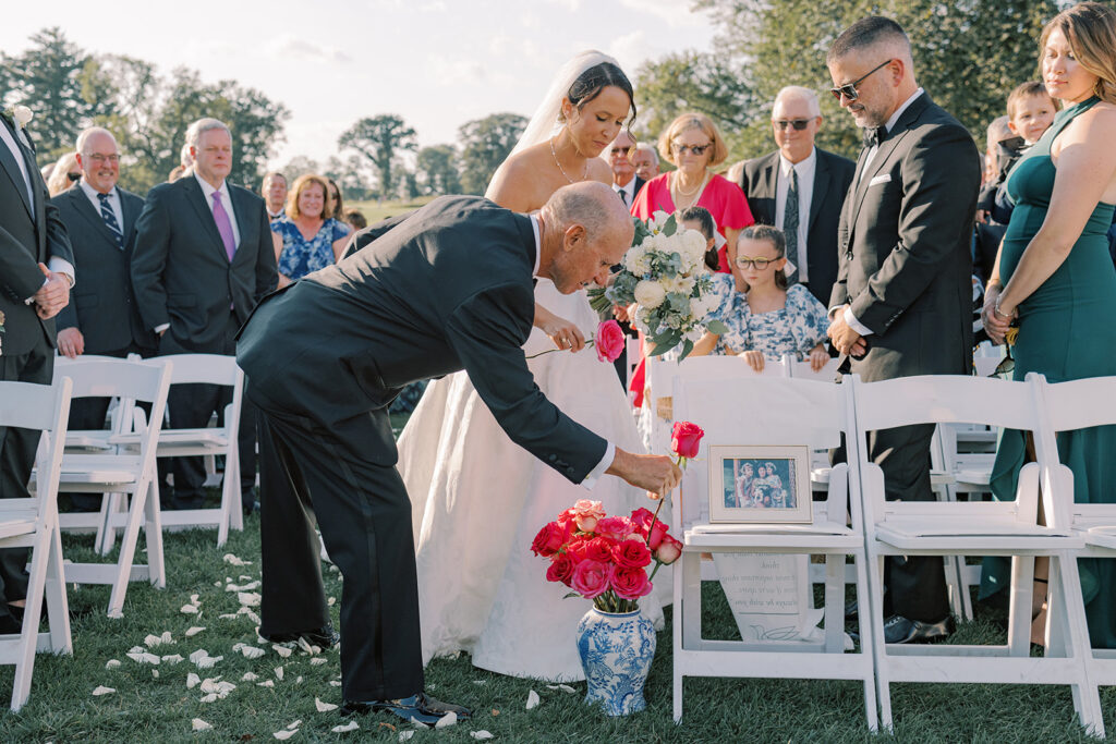 A family member places a pink rose into the blue and white china vase honoring the bride's late mother, Jeanne, during the ceremony