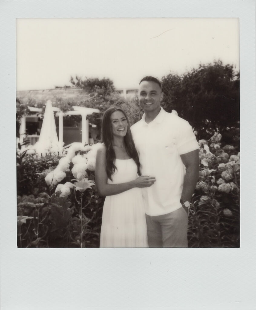 Sepia-toned Polaroid portrait of Carolyn and Zach smiling together in the Congress Hall gardens at their Cape May engagement session