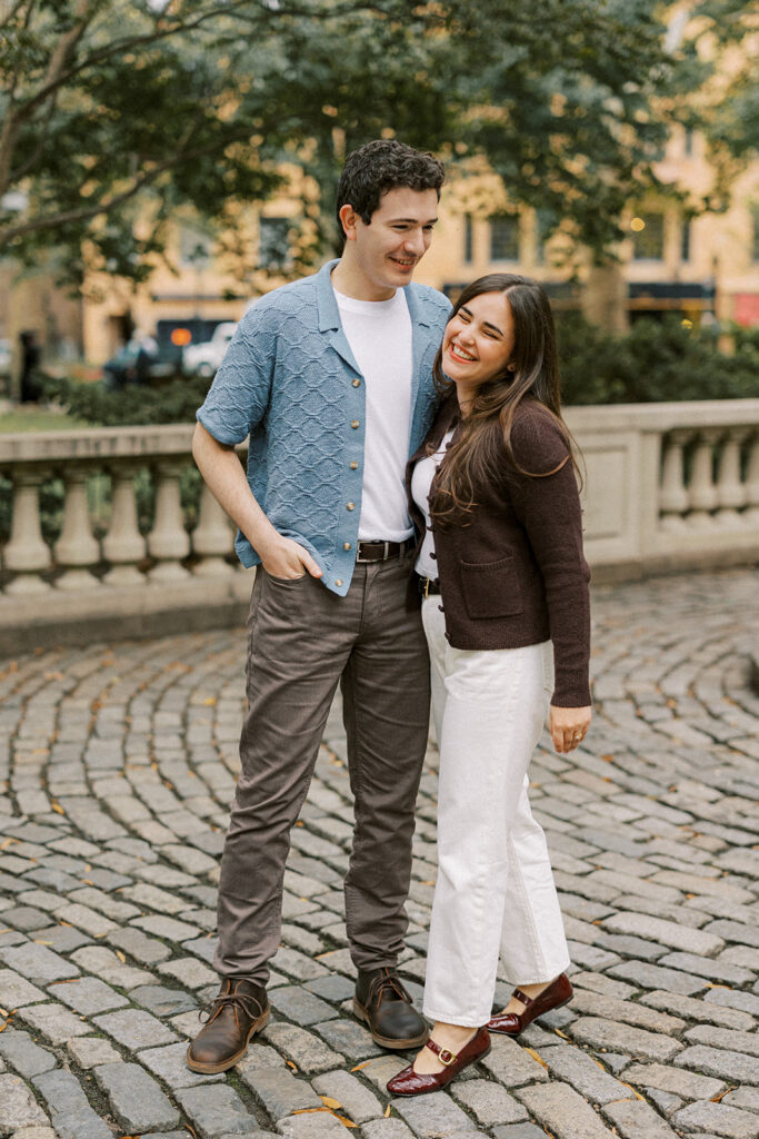 Amy and Chas on a tree-lined Philadelphia sidewalk in their first engagement outfits