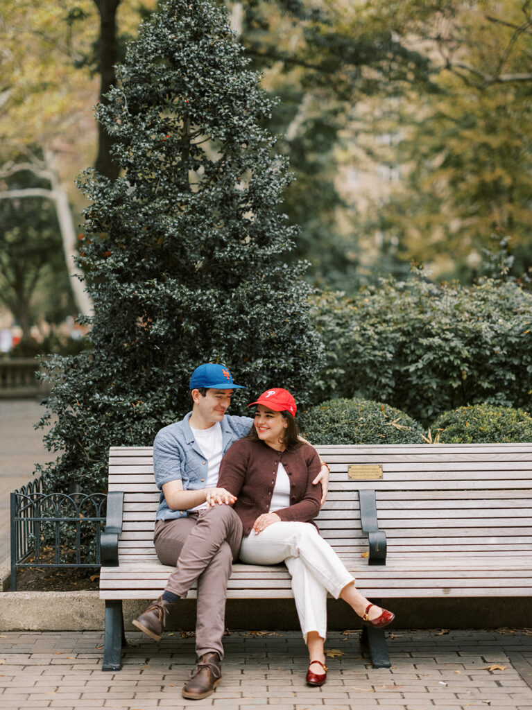Amy and Chas wearing baseball caps and sharing a quiet moment on a park bench at Rittenhouse Square