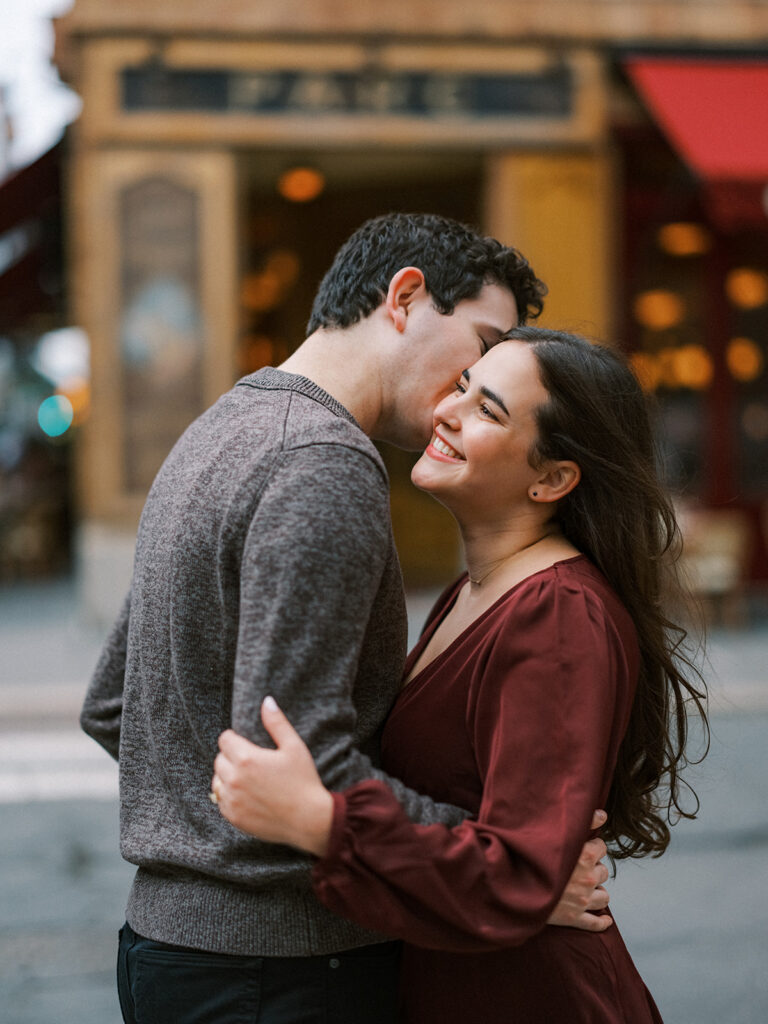 Chas kisses Amy's cheek outside a Rittenhouse Square café during their fall engagement photos in Philadelphia