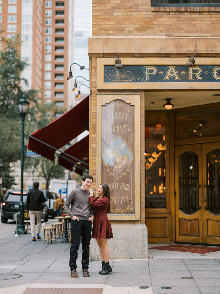 Couple standing outside a Rittenhouse Square café during their fall engagement photos in Philadelphia